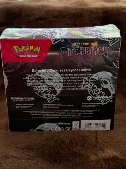 Pokémon Mega Evolution Pitch Black trading card game box back, showing the product packaging on a brown furry surface.
