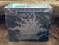 Pokémon Trading Card Game Elite Trainer Box for Pitch Black from the Mega Evolution expansion, sealed in its original plastic shrink wrap and photographed on a brown textured surface.
