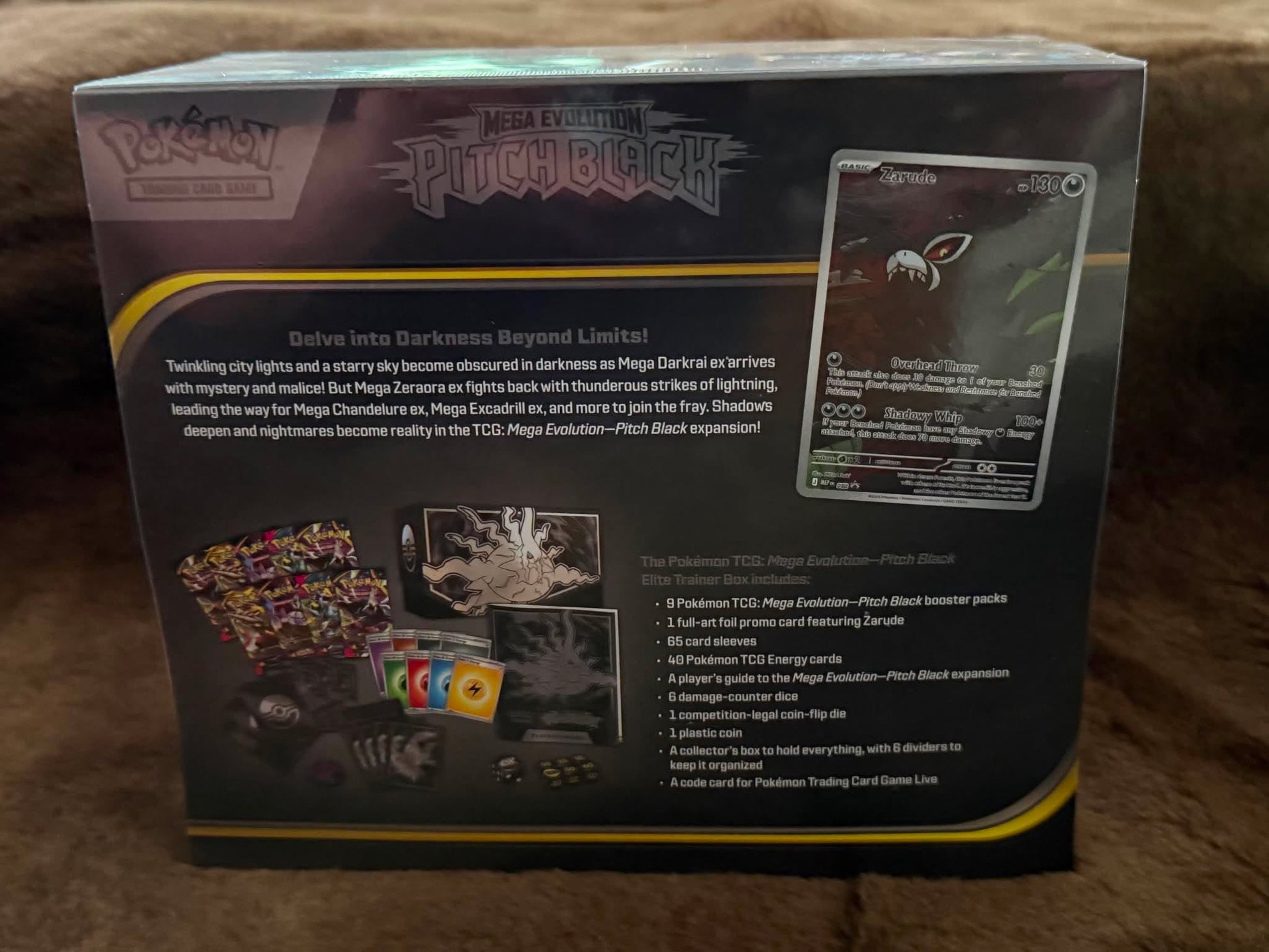 The back of a Pokémon TCG Mega Evolution Pitchblock box, showing product details, artwork, and a card preview on a brown fabric background.