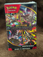 A sealed Pokémon Trading Card Game booster box for Mega Evolution Pitch Black, photographed standing upright on a brown textured surface. The box art is highly colorful with black, red, yellow, blue, and white elements, and the Pokémon logo is clearly visible at the top left.